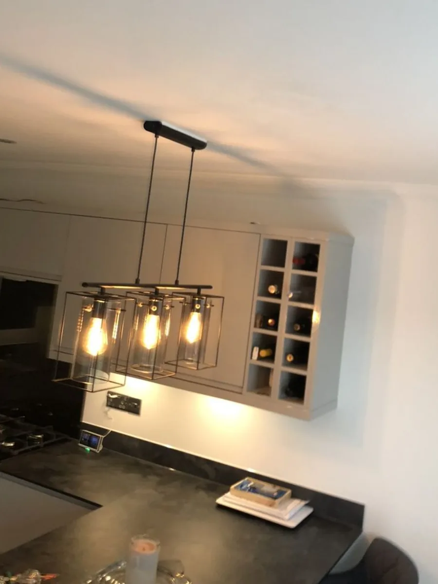 Three caged pendant lights over a kitchen island, the hob at the edge of the frame