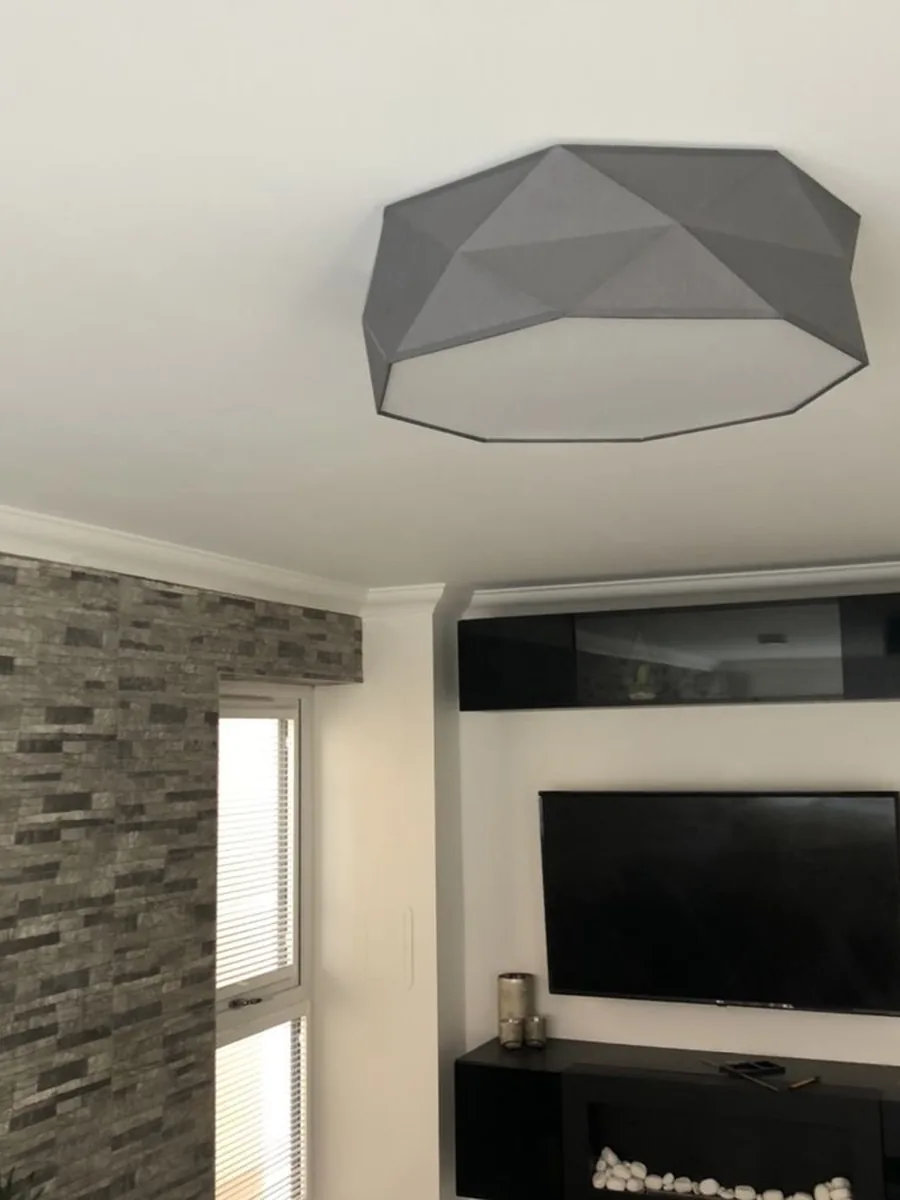 Lighting installation: a faceted grey ceiling pendant in a lounge, with the TV and media unit below