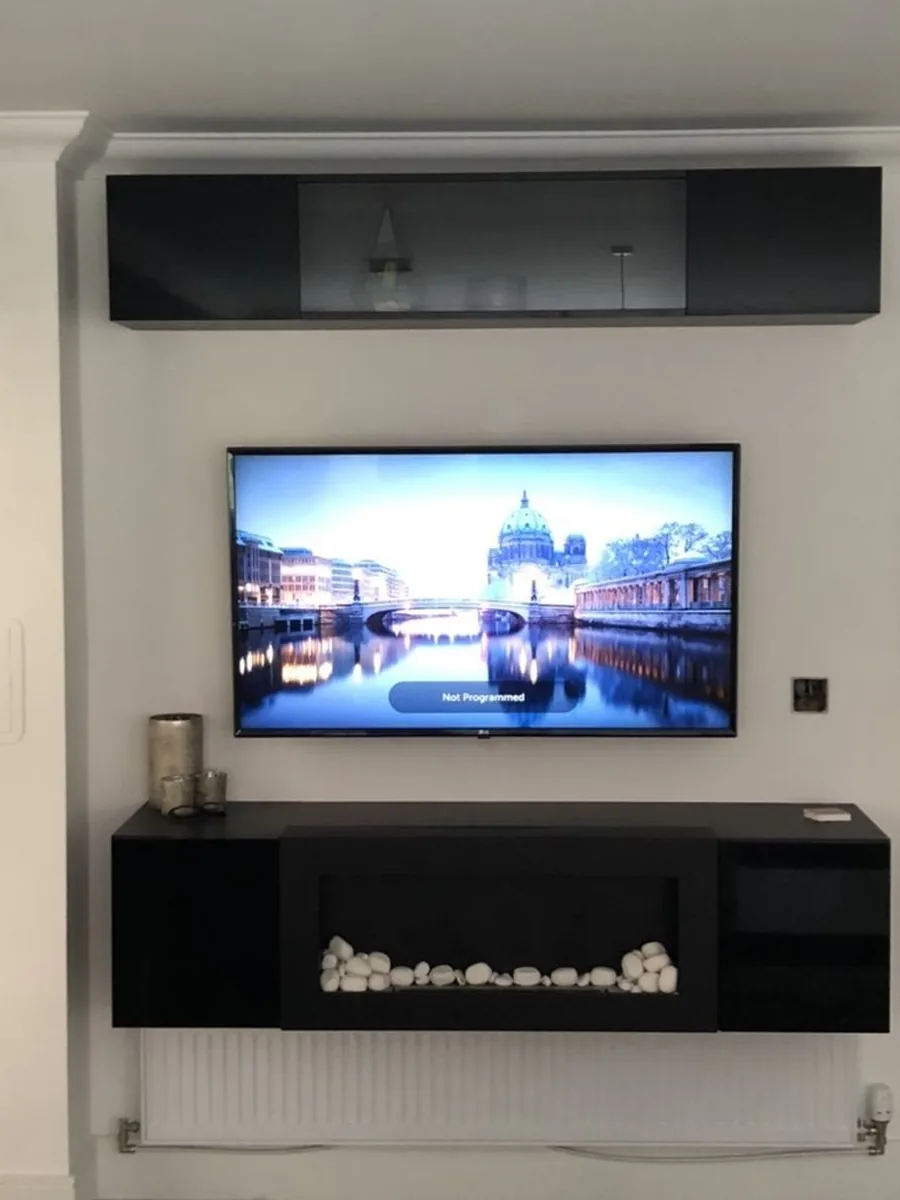 A TV mounted flush on a wall with no visible cables, a floating unit and fire beneath
